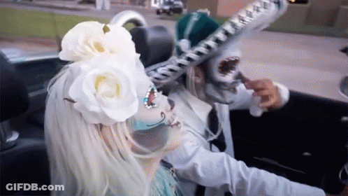 A Woman With A Flower In Her Hair Is Driving A Car GIF