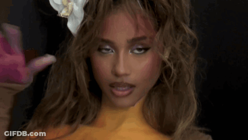 A Woman With A Flower In Her Hair Is Getting Her Hair Done . GIF