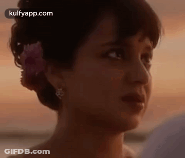 A Woman With A Flower In Her Hair Is Looking At A Man . GIF