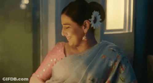 A Woman With A Flower In Her Hair Is Smiling While Holding A Baby . GIF