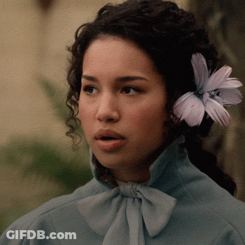 A Woman With A Flower In Her Hair Is Wearing A Blue Shirt GIF