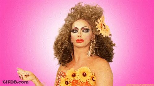A Woman With A Flower In Her Hair Is Wearing A Dress With Flowers On It GIF