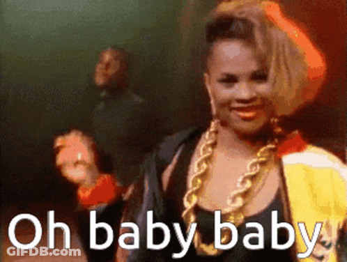 A Woman With A Gold Chain Around Her Neck Is Smiling With The Words Oh Baby Baby Below Her GIF