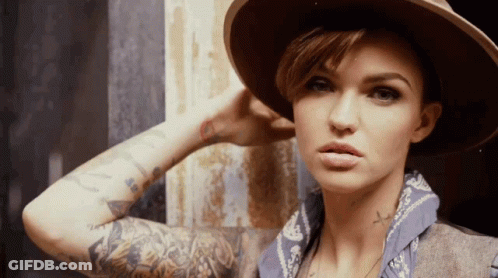 A Woman With A Hat And A Bandana Has A Cross Tattoo On Her Arm GIF