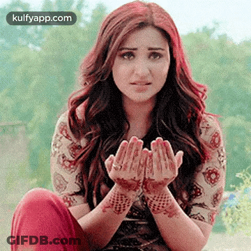 A Woman With A Henna Tattoo On Her Hands Is Sitting On The Ground With Her Hands Folded In Prayer . GIF
