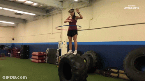 A Woman With A Hula Hoop On Top Of A Tire In A Gym With The Words Awesome Behind Her GIF