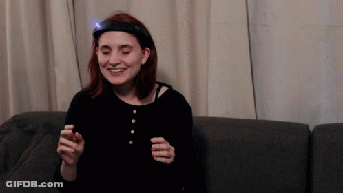 A Woman With A Light On Her Head Is Smiling GIF