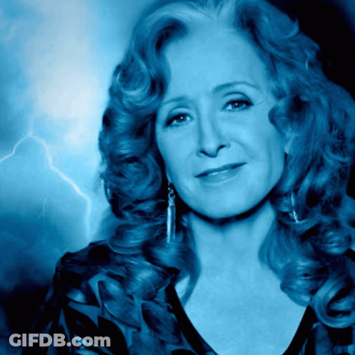 A Woman With A Lightning Bolt In The Background Looks At The Camera GIF