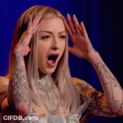 A Woman With A Lot Of Tattoos On Her Arms Is Making A Surprised Face With Her Mouth Open . GIF