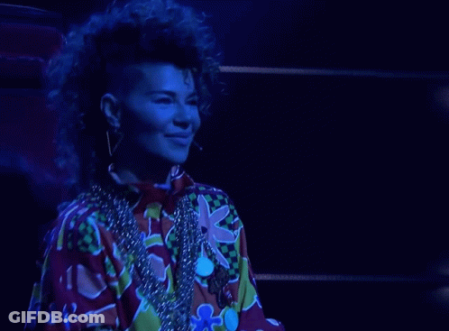 A Woman With A Mohawk Is Wearing A Colorful Shirt And A Necklace GIF