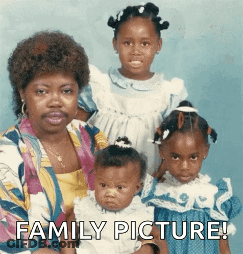 A Woman With A Mustache Is Holding A Baby And Two Girls With The Words Family Picture Below Them GIF