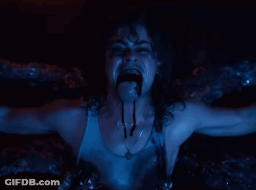 A Woman With A Necklace Around Her Neck Is Screaming In A Dark Room GIF
