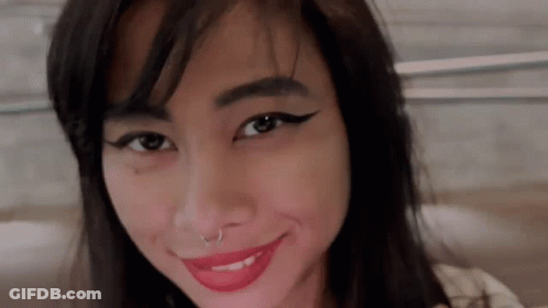 A Woman With A Nose Ring And Red Lipstick Is Smiling For The Camera . GIF