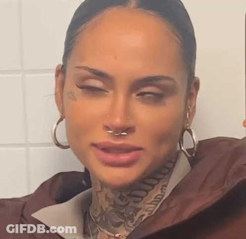 A Woman With A Nose Ring And Tattoos On Her Face Is Taking A Selfie . GIF