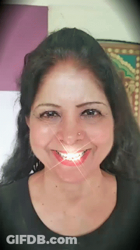A Woman With A Nose Ring Is Smiling With A Light Coming Out Of Her Mouth GIF