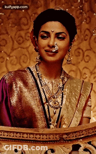 A Woman With A Nose Ring Is Wearing A Purple And Gold Sari And Jewelry . GIF