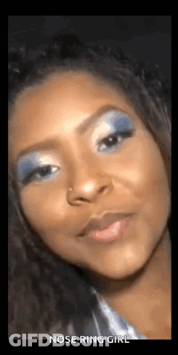 A Woman With A Nose Ring Is Wearing Blue Eye Shadow . GIF