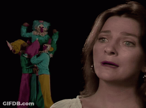 A Woman With A Nose Ring Looks At A Group Of Clowns On Stilts GIF