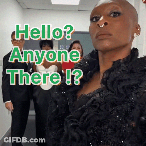 A Woman With A Nose Ring Stands In Front Of A Sign That Says Hello Anyone There ! GIF