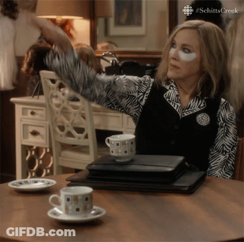 A Woman With A Patch On Her Eye Is Sitting At A Table With A Cup Of Coffee On It GIF
