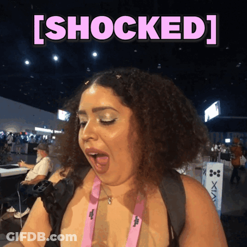 A Woman With A Pink Lanyard Around Her Neck Is Shocked GIF