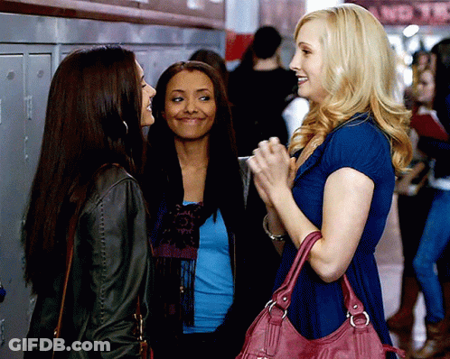 A Woman With A Pink Purse Is Talking To Two Other Women In A Hallway GIF