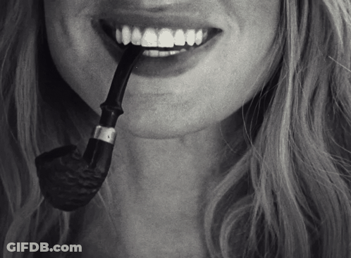 A Woman With A Pipe In Her Mouth And A Smile On Her Face GIF