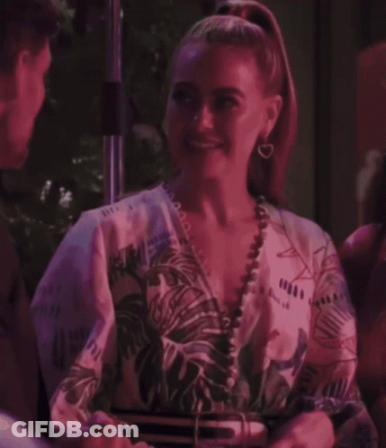 A Woman With A Ponytail Is Smiling And Wearing A Floral Shirt GIF