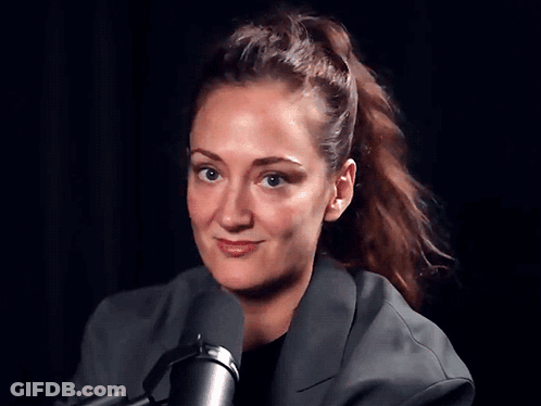 A Woman With A Ponytail Is Standing In Front Of A Microphone GIF