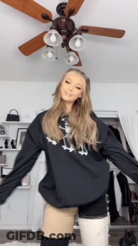 A Woman With A Prosthetic Leg Is Dancing In A Room With A Ceiling Fan In The Background GIF