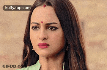 A Woman With A Red Dot On Her Forehead Is Making A Face . GIF