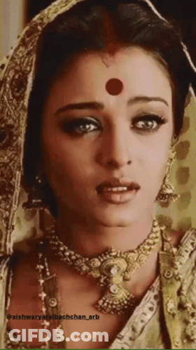 A Woman With A Red Dot On Her Forehead Is Wearing A Gold Necklace GIF