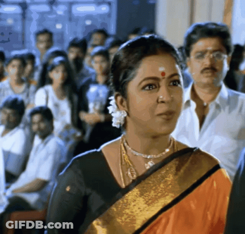 A Woman With A Red Dot On Her Forehead Stands In A Crowd Of People GIF