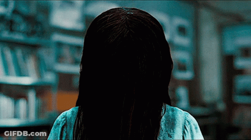 A Woman With A Ring In Her Hair Is Standing In A Library GIF