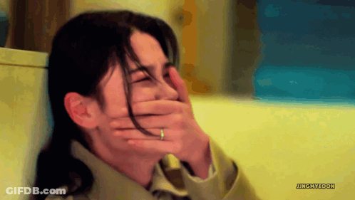 A Woman With A Ring On Her Finger Covers Her Mouth With Her Hand GIF