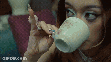 A Woman With A Ring On Her Finger Drinks From A Cup GIF