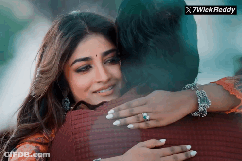 A Woman With A Ring On Her Finger Is Hugging A Man With A 7Wick Reddy Logo In The Corner GIF