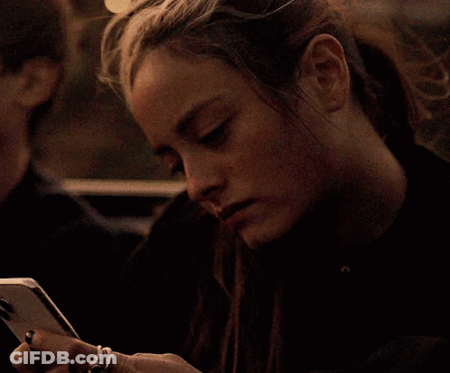 A Woman With A Ring On Her Finger Is Looking At Her Cell Phone GIF