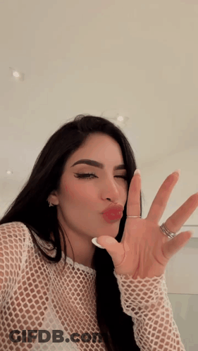 A Woman With A Ring On Her Finger Is Making A Kissing Face GIF