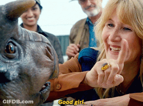 A Woman With A Ring On Her Finger Is Pointing At A Dinosaur With The Words " Good Girl " Below Her GIF