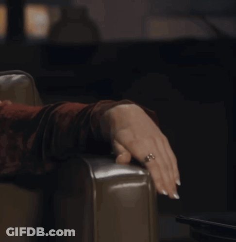A Woman With A Ring On Her Finger Is Sitting On A Chair GIF