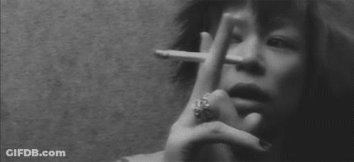 A Woman With A Ring On Her Finger Is Smoking A Cigarette In A Black And White Photo . GIF