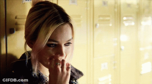 A Woman With A Ring On Her Finger Is Standing In Front Of A Row Of Lockers GIF