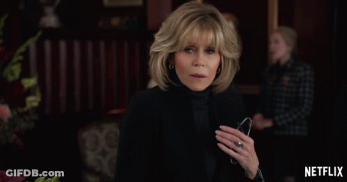 A Woman With A Ring On Her Finger Stands In Front Of A Netflix Ad GIF
