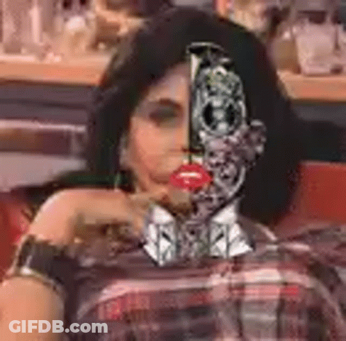 A Woman With A Robot Face On Her Face Is Sitting In A Chair . GIF