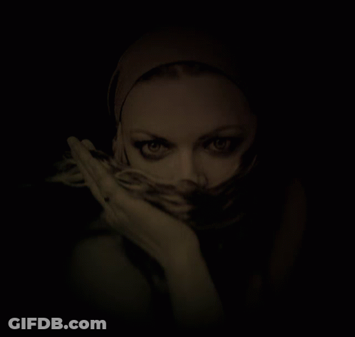 A Woman With A Scarf Around Her Face Looks At The Camera GIF