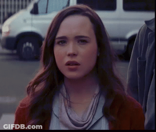 A Woman With A Scarf Around Her Neck Is Looking At The Camera GIF