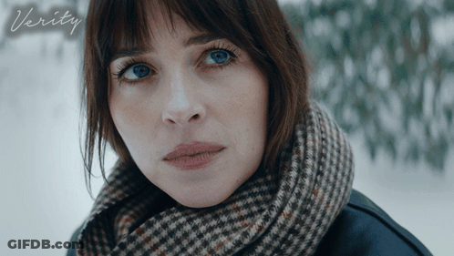 A Woman With A Scarf Around Her Neck Looks At The Camera With The Word Verity Below Her GIF