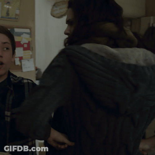 A Woman With A Scarf Around Her Neck Stands Next To Another Woman In A Kitchen GIF