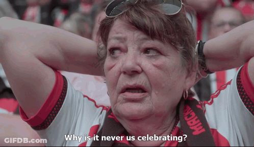A Woman With A Scarf That Says Mack On It Is Asking Why Is It Never Us Celebrating GIF
